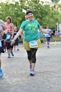 A woman runs accross a race finish line smiling