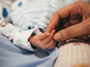 Adult hand holds a newborns hand