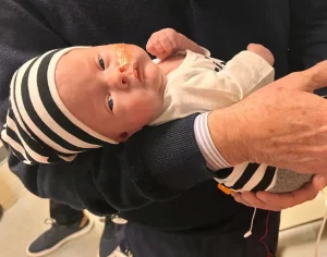 Dr. Crombleholme holds Thaddeus, a new baby, who underwent fetal surgery to repair spina bifida defect. 