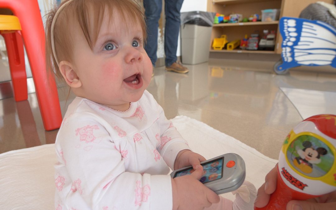 On-year-old baby plays with a remote control in a playroom