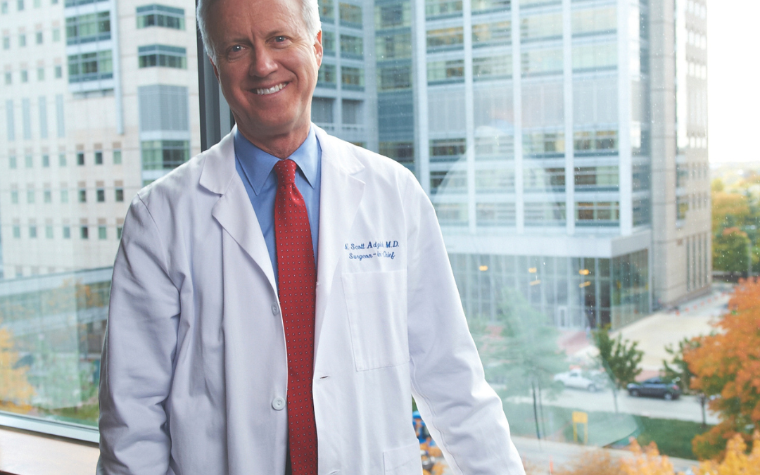 Male doctor stands by large window in the hospital smiling